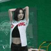 a woman in a twins jersey stands in front of a green fence