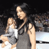 a girl in a plaid dress is standing in front of a crowd