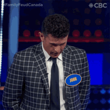 a man in a plaid suit and tie has a name tag that says john