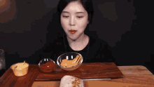 a woman is eating a burrito on a wooden cutting board with sauces and chips .
