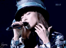 a woman singing into a microphone with a bs-r logo in the corner