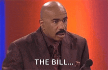 a bald man in a suit and tie is speaking into a microphone and saying `` the bill '' .