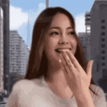 a woman is smiling and covering her mouth with her hands .