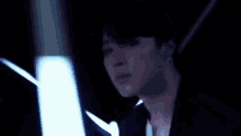 a close up of a man 's face in a dark room with glowing lights behind him .