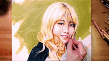 a drawing of a woman with blonde hair is being painted on a piece of paper