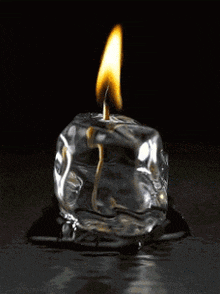 a lit ice cube candle is melting on a black surface