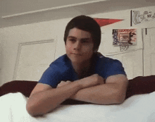 a man in a blue shirt is laying on a bed