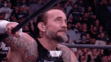 a wrestler is holding a bat in his hand in front of a crowd of people .