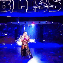 a female wrestler is standing on a stage holding a wrestling belt .
