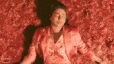 a woman in a pink jacket is laying in a pile of red sauce with an amazon prime arrow in the background