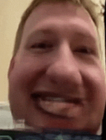 a close up of a man 's face smiling with his tongue out
