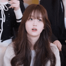 a woman with long brown hair and bangs looks up at something