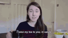 a woman is holding a mug and saying i raise my tea to you in salute
