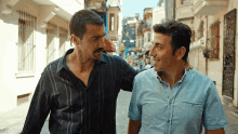 two men are walking down a street and one has his arm around the other 's shoulders