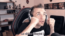 a man wearing headphones is sitting in front of a microphone and says le chieur eternel !