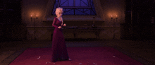a woman in a purple dress is standing in a room with candles