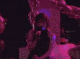 a woman in a black dress singing into a microphone in a dark room