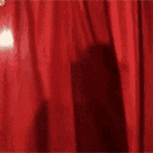 a close up of a red curtain with a person behind it .