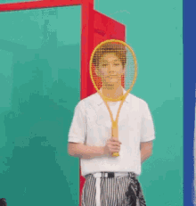 a man in a white shirt is holding a yellow tennis racket in front of his face