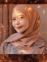 a woman wearing a hijab and plaid jacket is smiling for the camera .