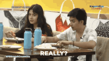 a man and a woman are sitting at a table with plates of food and a caption that says really