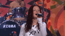 a woman singing in front of a tama drum