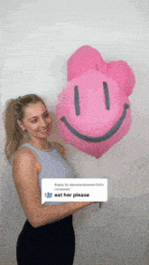 a woman holding a pink balloon with a smiley face
