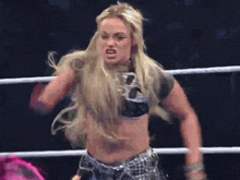 a female wrestler in a neon green polka dot outfit is jumping into the air