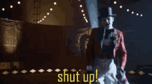 a man in a top hat is standing in front of a sign that says " shut up "