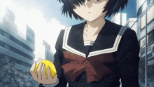 a girl in a school uniform is holding a lemon