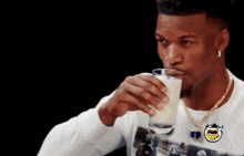 a man is drinking a glass of milk and looking at the camera .
