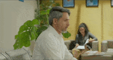 a man in a white shirt sits in a waiting room with a woman