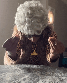a woman with a necklace that says queen is sitting at a table