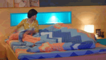 a woman is making a bed with a colorful comforter