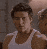 a man in a white tank top is talking to a woman and says i 'm a funny guy .