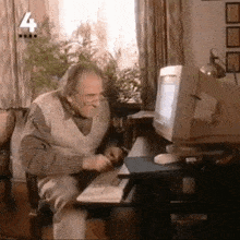 an old man sits at a desk in front of a computer with the number 4 on the bottom right