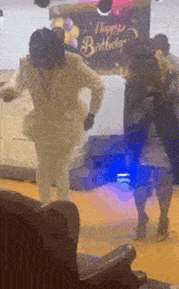 a group of people are dancing in front of a happy birthday sign .