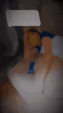 a blurred image of a person laying on a bed with a speech bubble above them
