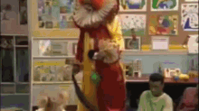 a clown is standing in front of a group of children in a room .