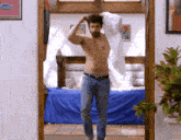 a shirtless man standing in a bedroom with a blue bed