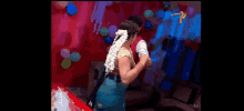 a man and a woman are dancing in a room with balloons and a tv logo in the corner .