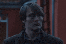 a close up of a man wearing glasses and a brown jacket