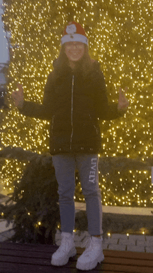 a girl wearing a santa hat and a jacket with the word lively on her pants