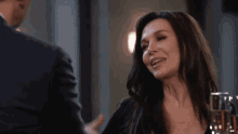 a woman in a black dress is smiling and talking to a man in a suit .