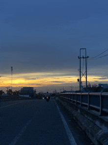 a person riding a motorcycle on a highway with a sunset in the background