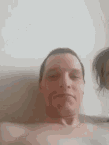 a man without a shirt is making a funny face in front of a woman .