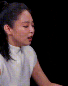 a close up of a woman 's face with her eyes closed and a white shirt on .