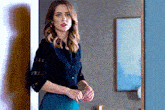 a woman in a black shirt and green skirt is standing in a room next to a mirror .