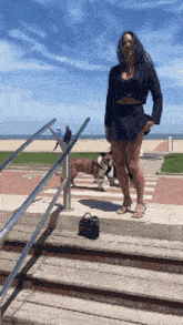 a woman in a black dress is walking a dog
