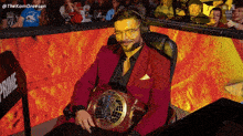 a man in a red suit is sitting in a chair with a belt around his waist